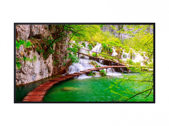 Wooden walkway curving over clear green water beneath cascading waterfalls, surrounded by lush greenery and rocky cliffs in a peaceful nature setting at Plitvice Lakes National Park.