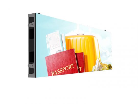 Large digital display screen featuring a travel-themed image with passports, boarding passes, and a yellow suitcase set against a bright blue sky background; the screen is shown from an angle to highlight its slim profile. Perfect for advertising travel or airline services.