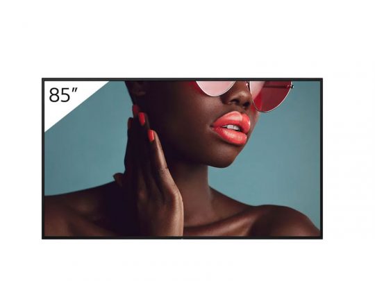 Nahaufnahme einer Person mit dunkler Haut, pinker Sonnenbrille, korallfarbenem Lippenstift und passenden lackierten Fingernägeln, die den Hals berührt - dargestellt auf einem 85-Zoll-Bildschirm zum Mieten oder Kaufen.